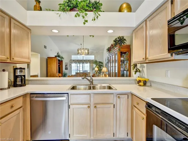 Kitchen featuring black appliances, a peninsula, vaulted ceiling, light brown cabinetry, and recessed lighting