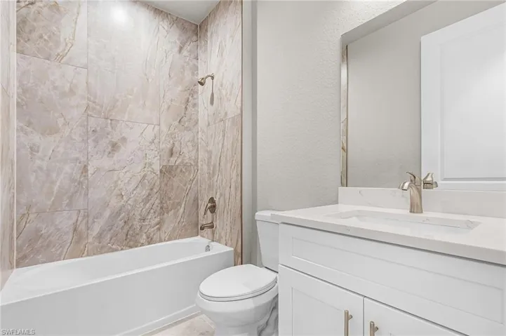 Bathroom with shower / bath combination, a textured wall, and vanity