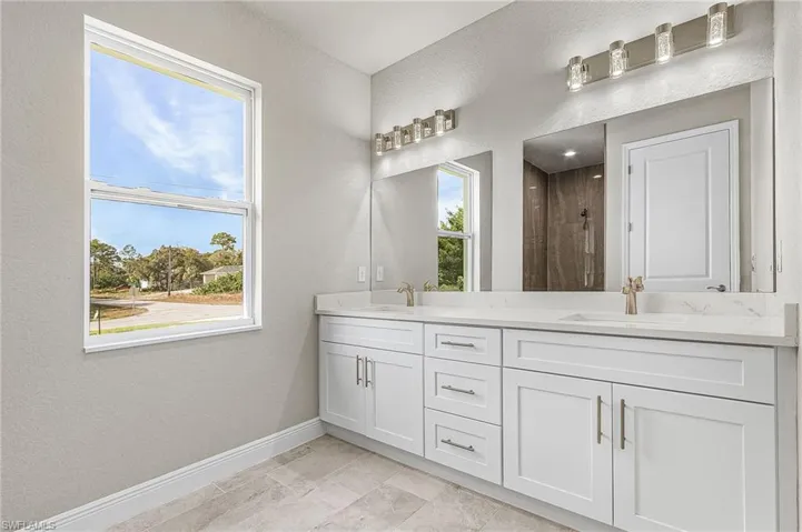 Full bathroom with a textured wall, double vanity, and tiled shower