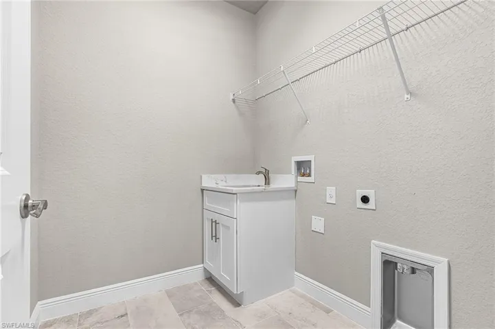Laundry area featuring washer hookup, cabinet space, electric dryer hookup, a textured wall, and light tile patterned floors