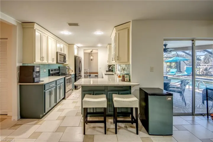 Kitchen with a kitchen breakfast bar, stainless steel appliances, light stone counters, green cabinets, and recessed lighting