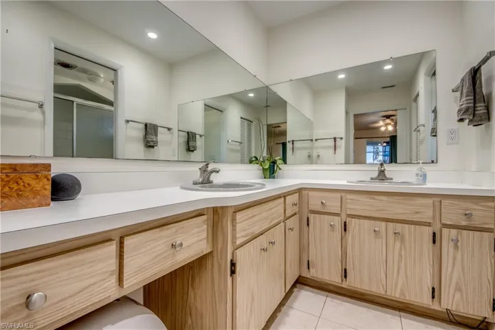 Bathroom with double vanity, a shower stall, light tile patterned floors, recessed lighting, and ceiling fan