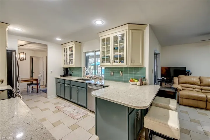 Kitchen with light stone countertops, glass insert cabinets, open floor plan, a peninsula, and stainless steel appliances