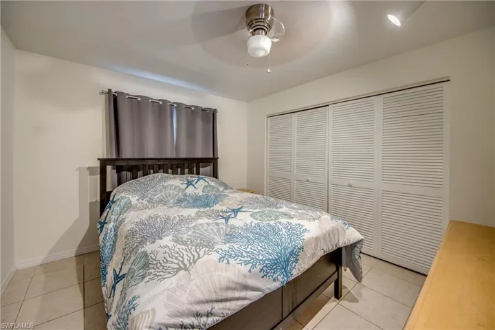 Bedroom with a closet, light tile patterned floors, and ceiling fan