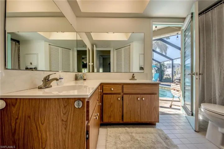 Full bath featuring a closet, double vanity, curtained shower, and light tile patterned flooring