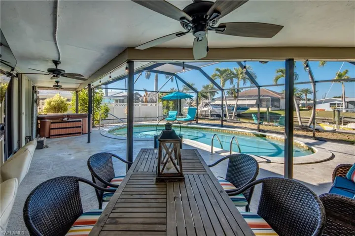 View of swimming pool featuring a hot tub, a patio, a sunroom, glass enclosure, and outdoor dining space