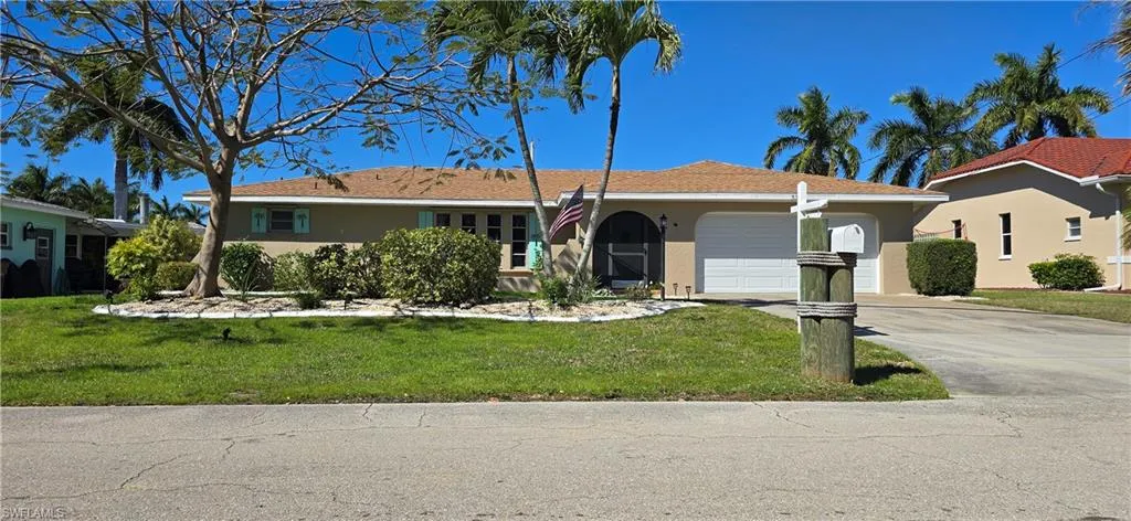 Single story home with a garage, driveway, a front yard, and stucco siding