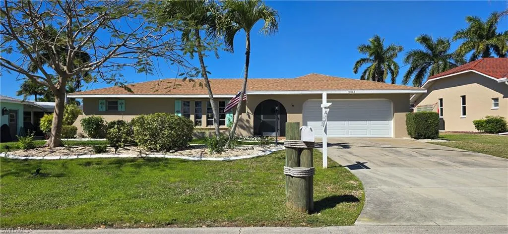 Single story home featuring a garage, stucco siding, driveway, and a front yard