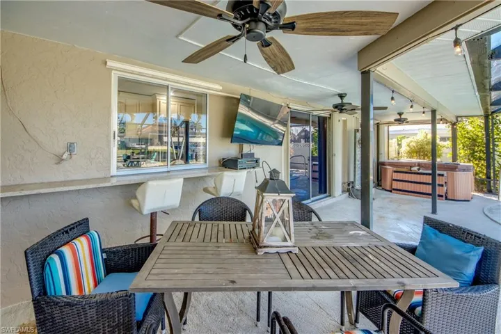 View of patio / terrace with outdoor dining space, a hot tub, and a ceiling fan