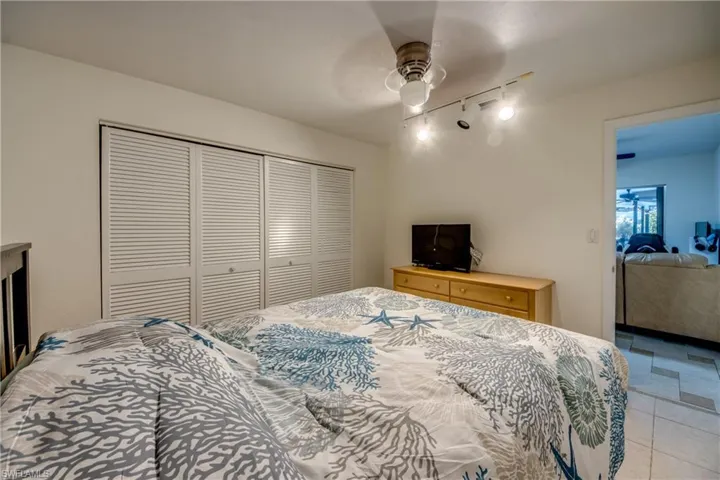 Tiled bedroom with a closet, track lighting, and ceiling fan