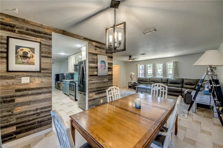 Dining space with a chandelier, wooden walls, and a ceiling fan