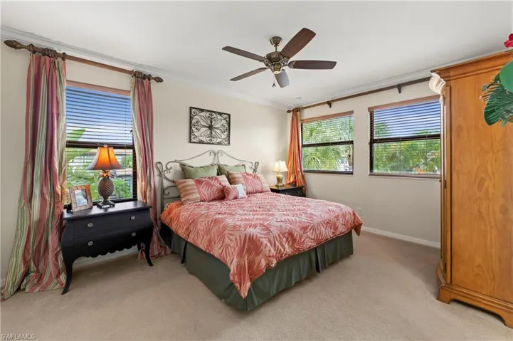 Carpeted room featuring multiple windows with blinds, crown molding, and a ceiling fan