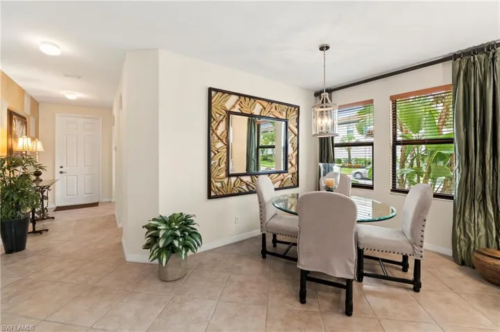 Dining area featuring a glass-top table, upholstered chairs, and a contemporary chandelier