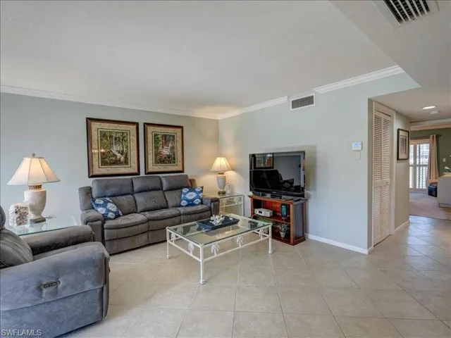 Tiled living room featuring ornamental molding and baseboards