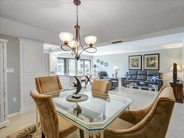 Dining space featuring light tile patterned flooring, a chandelier, and crown molding