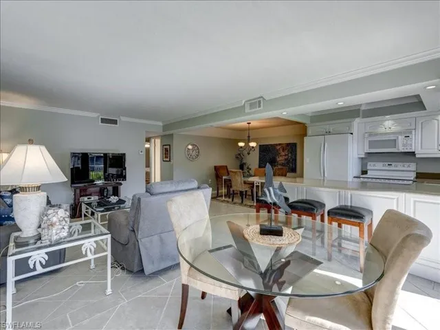 Dining space with crown molding, a chandelier, light tile patterned flooring, and recessed lighting