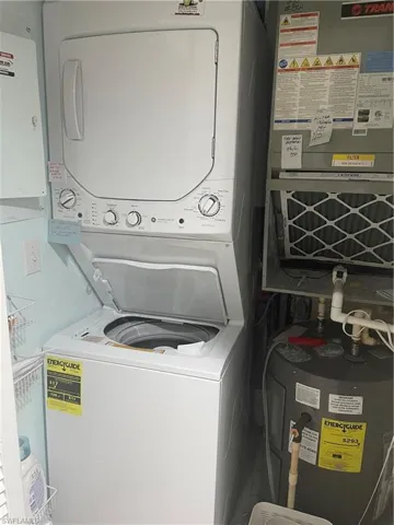 Laundry area featuring water heater, stackedwasher / dryer, and heating unit
