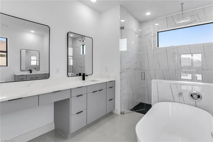 Full bathroom with a freestanding bath, a shower stall, double vanity, and recessed lighting