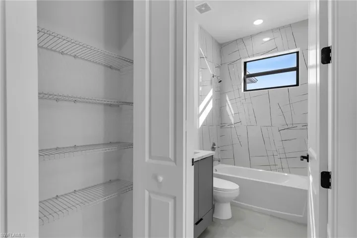 Bathroom featuring toilet, bathing tub / shower combination, and a spacious closet