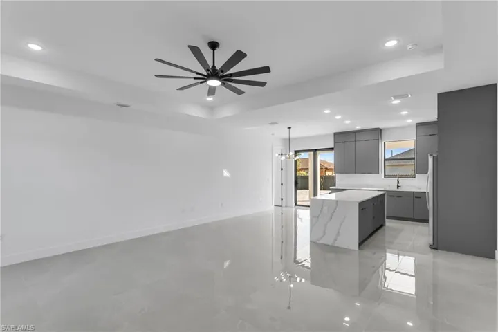 Kitchen featuring modern cabinets, gray cabinetry, a raised ceiling, a center island, and recessed lighting