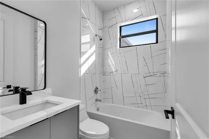 Bathroom featuring toilet, vanity, and bathtub / shower combination