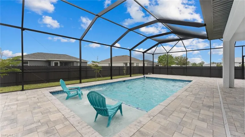 View of swimming pool featuring a patio area, a fenced backyard, and glass enclosure
