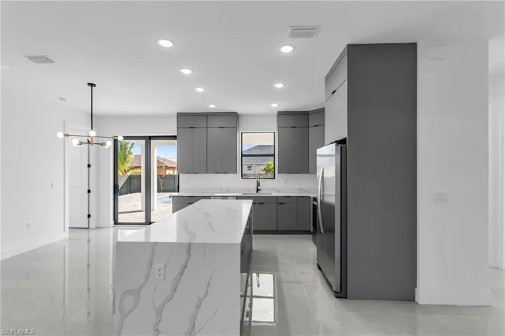 Kitchen featuring gray cabinets, freestanding refrigerator, modern cabinets, a kitchen island, and recessed lighting