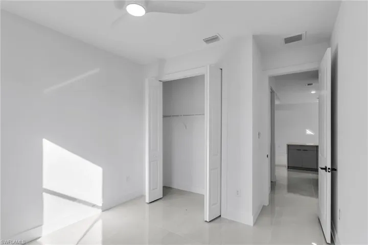 Unfurnished bedroom featuring light tile patterned floors, a closet, baseboards, and ceiling fan