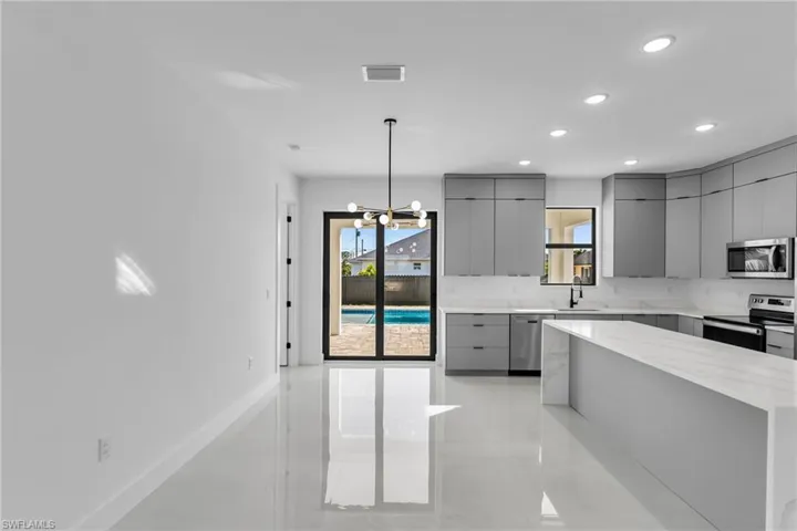 Kitchen featuring gray cabinetry, stainless steel appliances, modern cabinets, light tile patterned floors, and recessed lighting