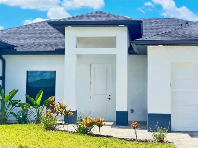 Doorway to property featuring a shingled roof, stucco siding, and a garage