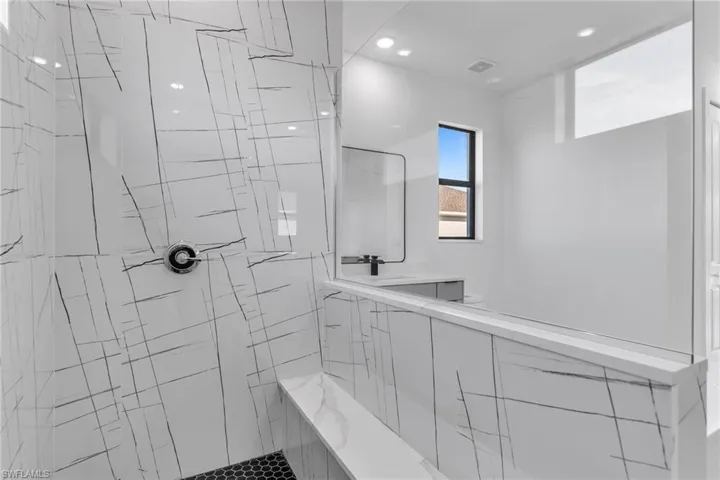Bathroom featuring a tile shower, a sink, and recessed lighting