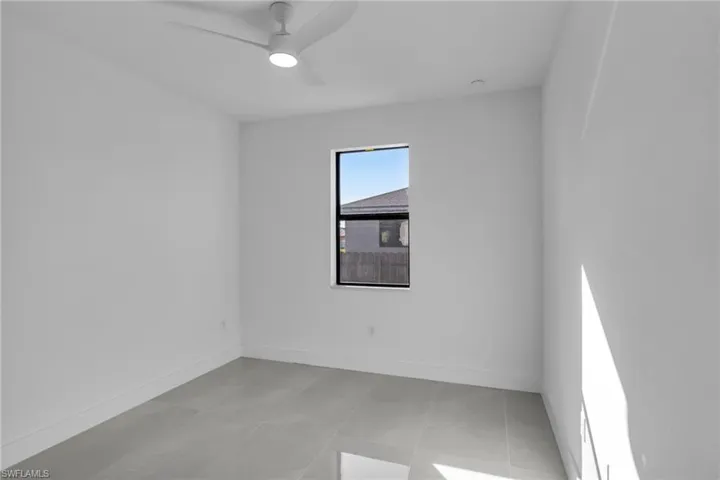 Empty room featuring a ceiling fan, baseboards, and light tile patterned floors