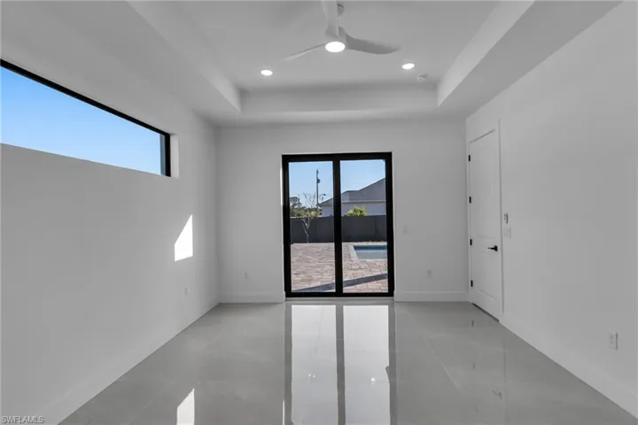 Empty room featuring a raised ceiling, healthy amount of natural light, ceiling fan, baseboards, and recessed lighting