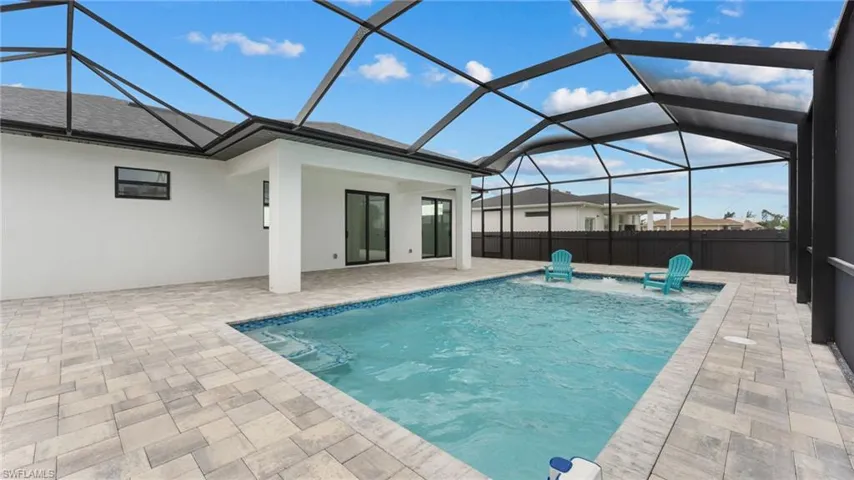 View of pool with a patio area and glass enclosure