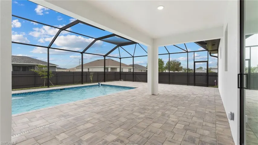 View of pool featuring a patio, a fenced backyard, and glass enclosure