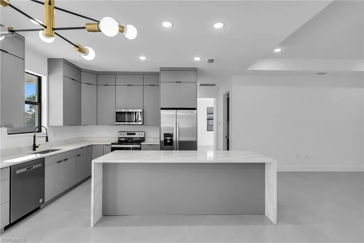 Kitchen featuring stainless steel appliances, gray cabinetry, a sink, modern cabinets, and a kitchen island