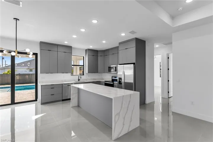 Kitchen featuring stainless steel appliances, gray cabinetry, modern cabinets, a sink, and recessed lighting