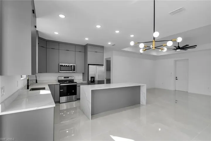 Kitchen with appliances with stainless steel finishes, gray cabinets, a sink, recessed lighting, and a kitchen island