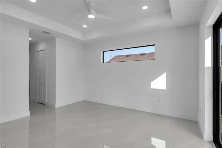 Spare room featuring a raised ceiling, ceiling fan, recessed lighting, and baseboards