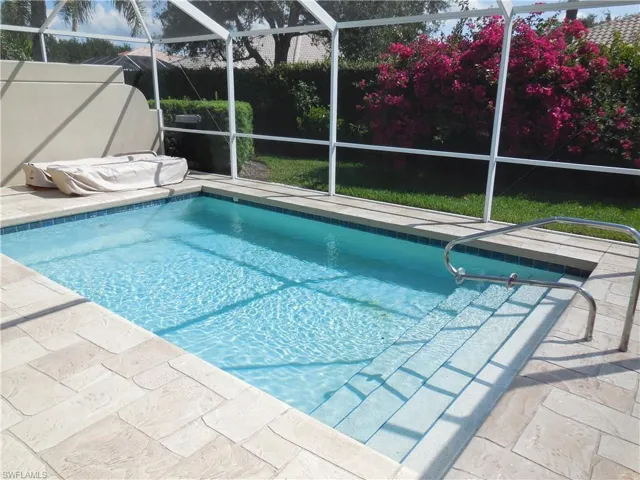View of swimming pool with glass enclosure and a patio area