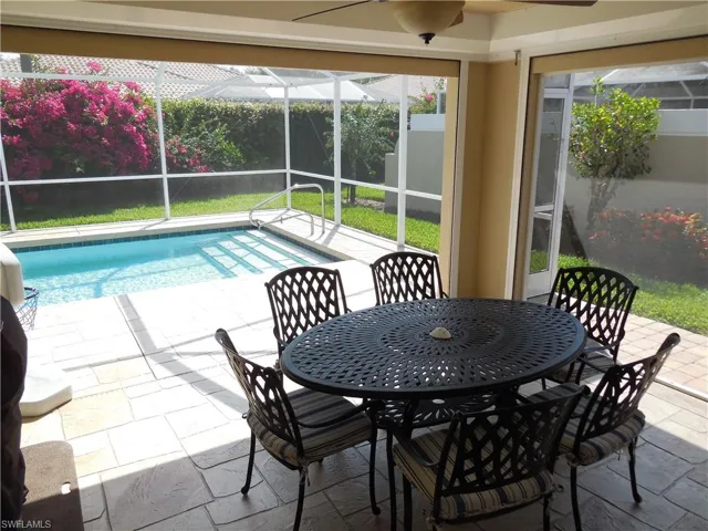 View of swimming pool featuring a patio, glass enclosure, and ceiling fan