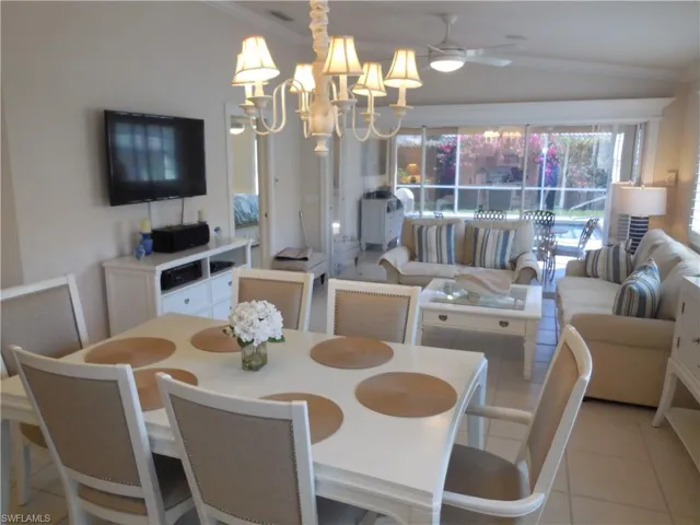Dining space featuring lofted ceiling, ceiling fan with notable chandelier, light tile flooring, and ornamental molding