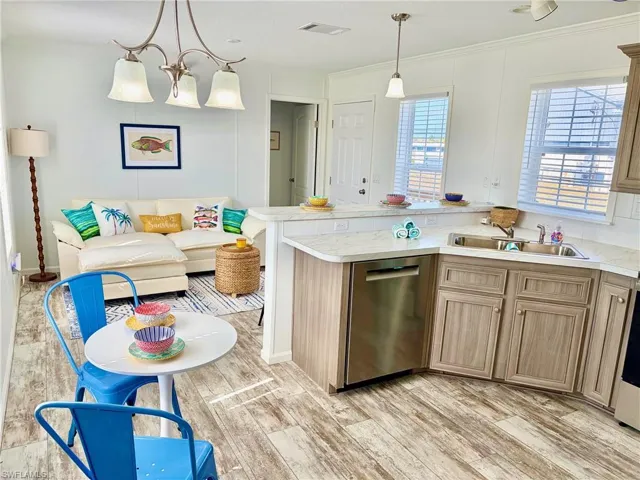 Kitchen with a peninsula, light countertops, dishwasher, decorative light fixtures, and crown molding