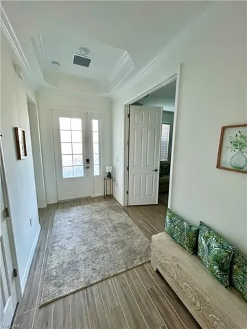 Entrance foyer featuring a tray ceiling, crown molding, and wood-type flooring Choice of Glass doors or new wood doors.