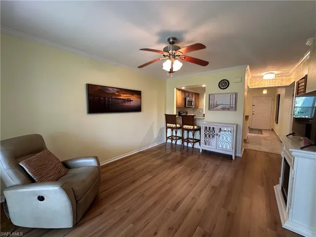 Living room with crown molding, wood-type flooring, and ceiling fan