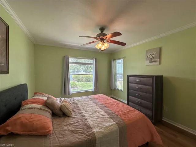 Bedroom featuring dark wood-type flooring, ornamental molding, and ceiling fan