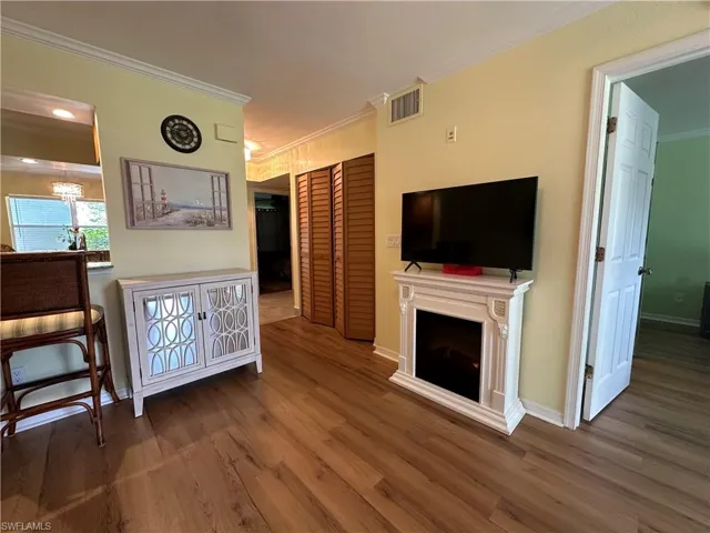 Living room featuring an inviting chandelier, dark hardwood / wood-style floors, and crown molding