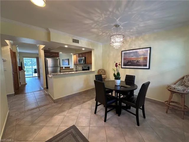 Dining area with crown molding, sink, light tile floors, and a chandelier