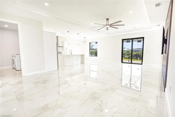 Spare room with a raised ceiling, ceiling fan, crown molding, sink, and separate washer and dryer