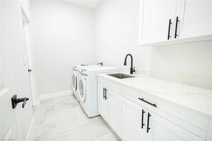Clothes washing area with cabinets, separate washer and dryer, and sink